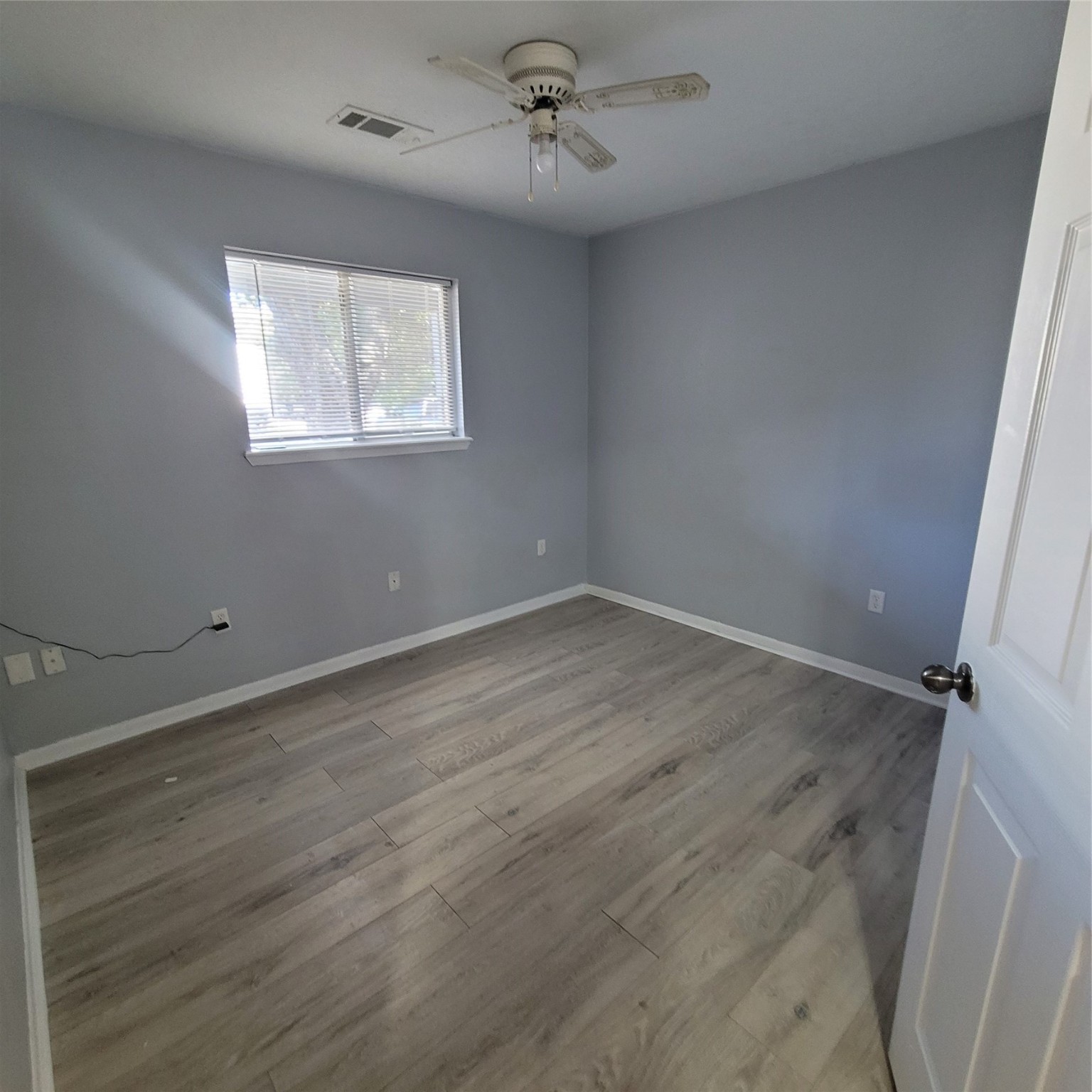 4508 15th Street Bacliff, TX 77518 - Photo 7 of 17 an empty room with wooden floor ceiling fan and windows