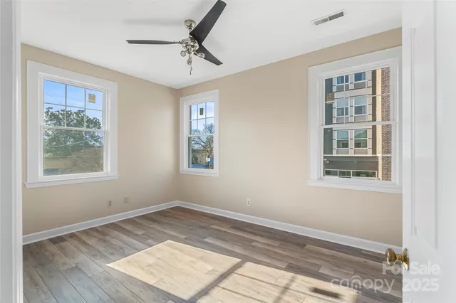 a view of an empty room with a window and wooden floor