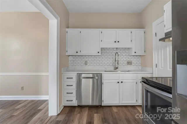 a kitchen with granite countertop white cabinets and stainless steel appliances