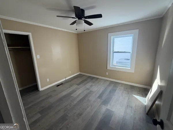 a view of empty room with wooden floor and fan