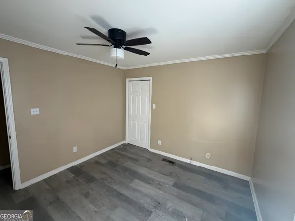 an empty room with wooden floor ceiling fan and window