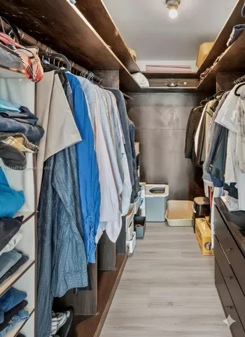 a view of walk in closet with clothes and shoes