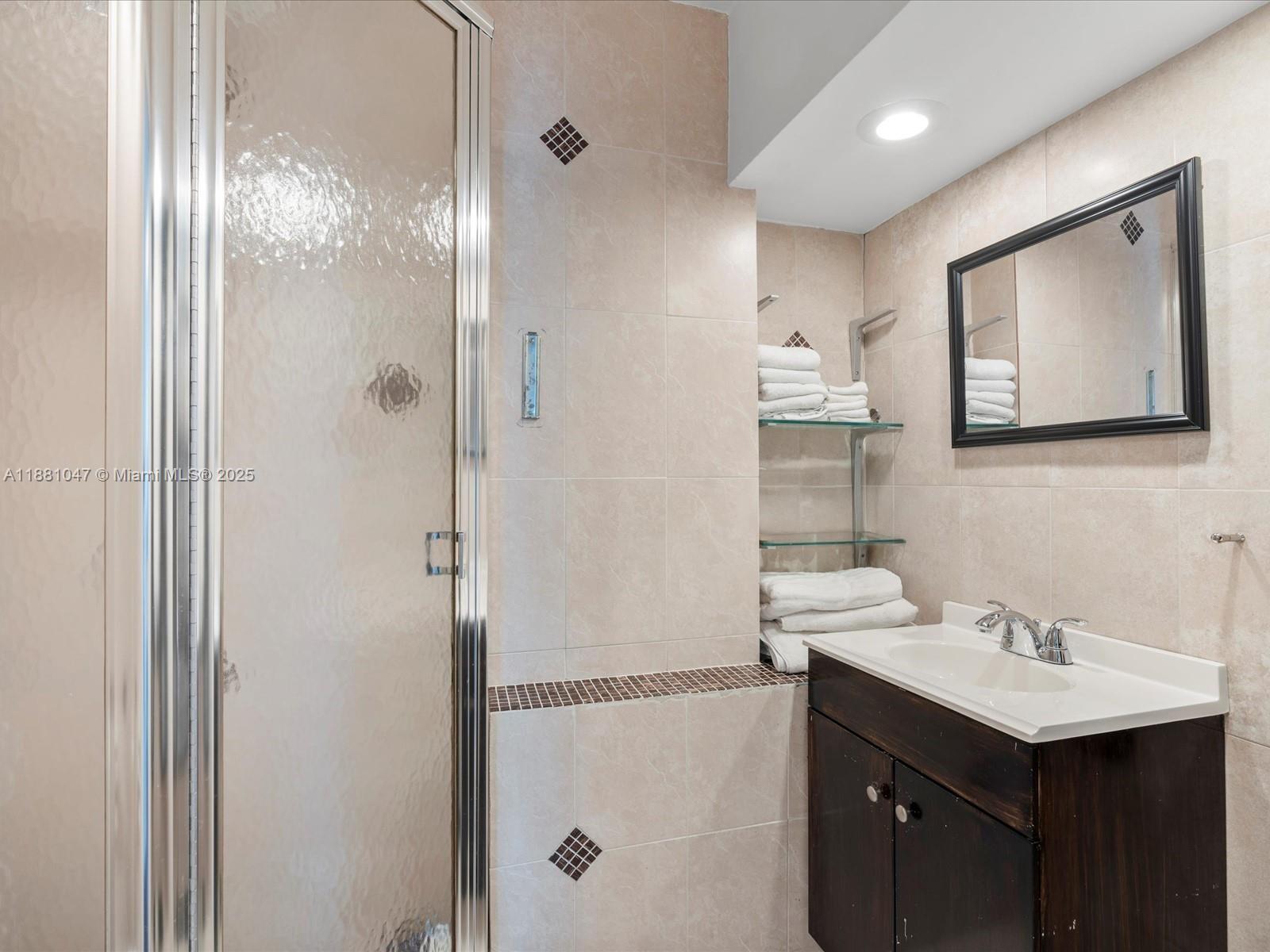 2655 Collins Avenue, Unit 510 Miami Beach, FL 33140 - Photo 19 of 23 a bathroom with a sink mirror and a shower
