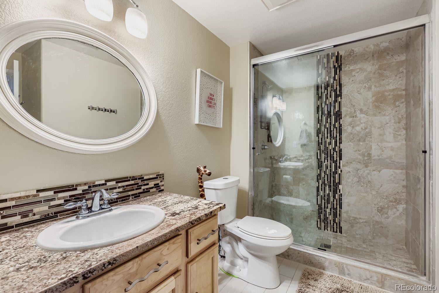 10752 Zuni Drive Denver, CO 80234 - Photo 24 of 27 a bathroom with a granite countertop toilet a sink and a mirror