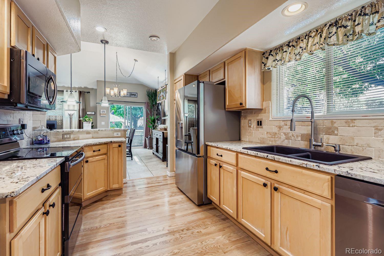 10752 Zuni Drive Denver, CO 80234 - Photo 9 of 27 a kitchen with stainless steel appliances granite countertop a sink stove and refrigerator