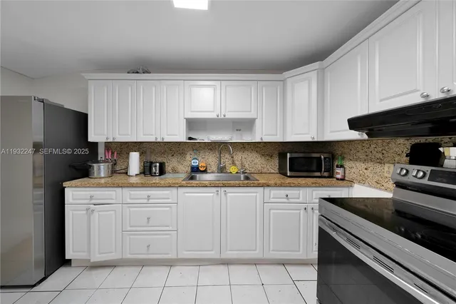 a kitchen with white cabinets and appliances