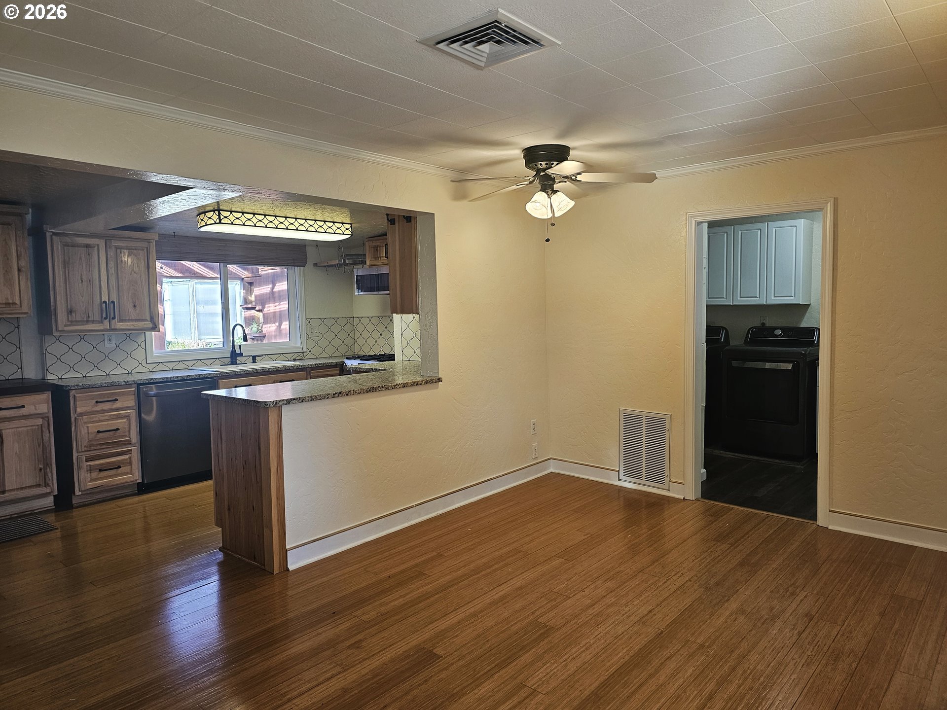 237 Wharf Street Brookings, OR 97415 - Photo 4 of 27 an empty room with wooden floor a ceiling fan and kitchen view