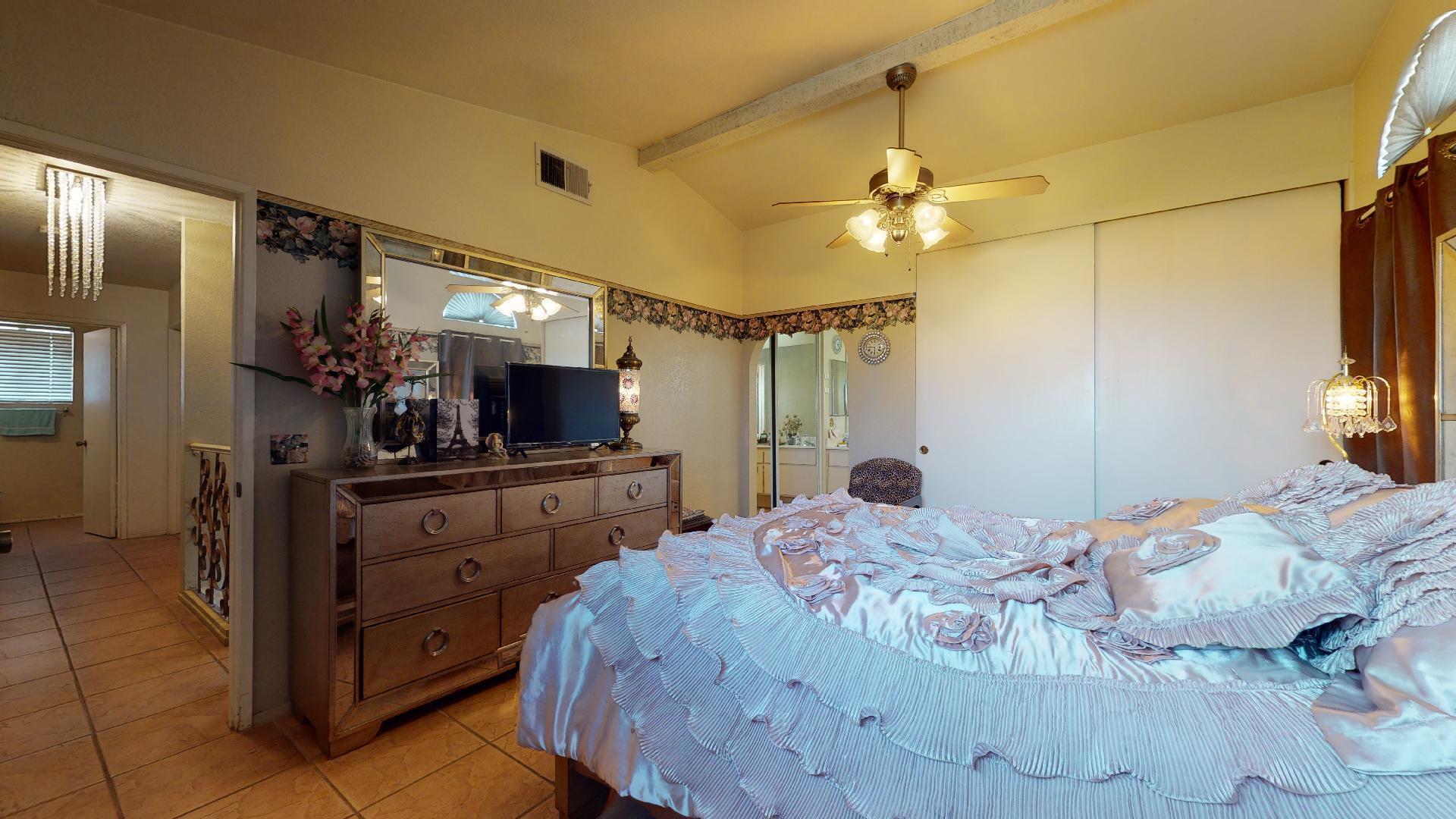 45808 Sutter Creek Road Indio, CA 92201 - Photo 23 of 55 a bedroom with a bed a chandelier and a flat screen tv