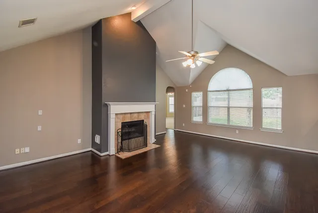 an empty room with wooden floor a chandelier fan and a fireplace