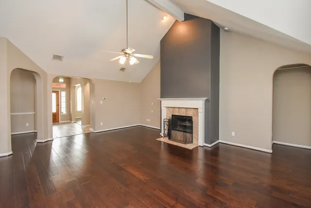 a view of an empty room with wooden floor and a fireplace