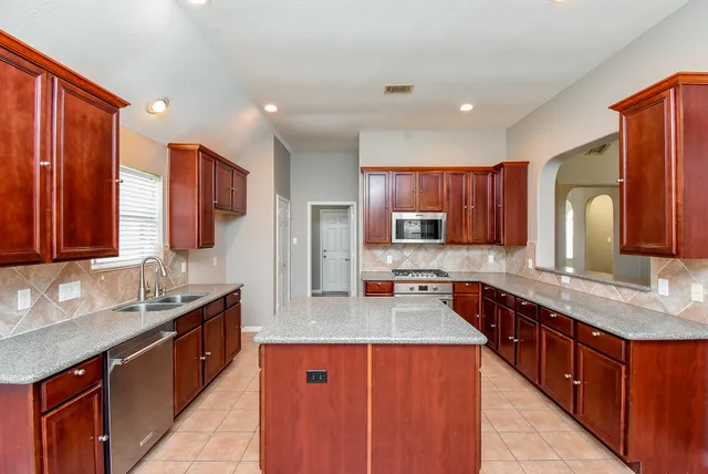 a large kitchen with stainless steel appliances microwave a sink and cabinets