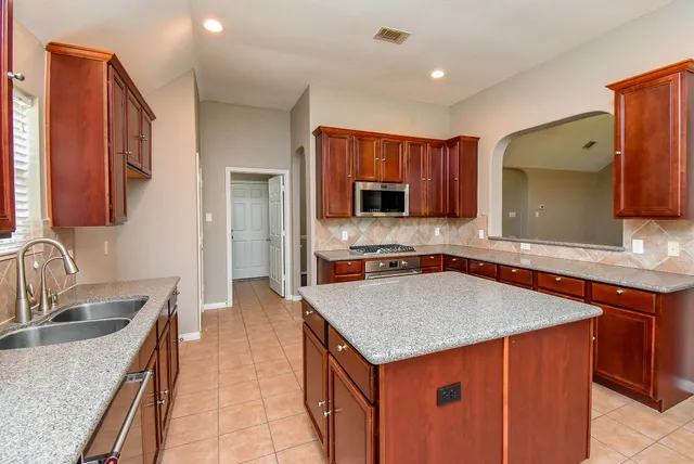 a kitchen with stainless steel appliances granite countertop a sink stove and refrigerator
