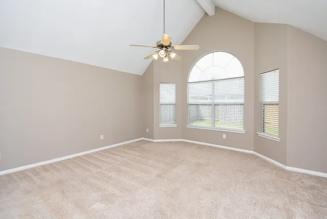 an empty room with chandelier fan and windows