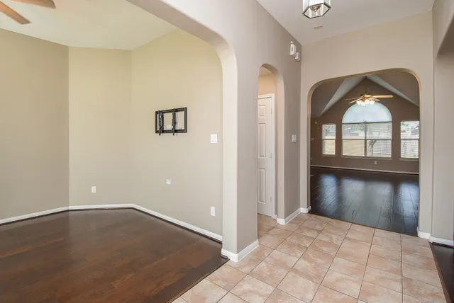 an empty room with wooden floor cabinet and windows