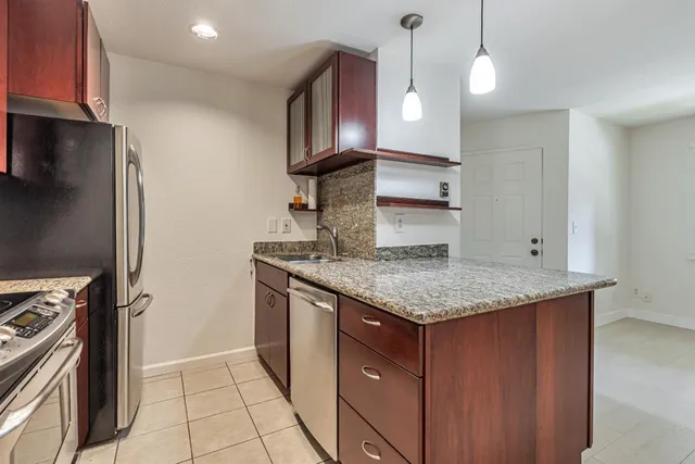 a kitchen with stainless steel appliances granite countertop a sink a refrigerator and a stove