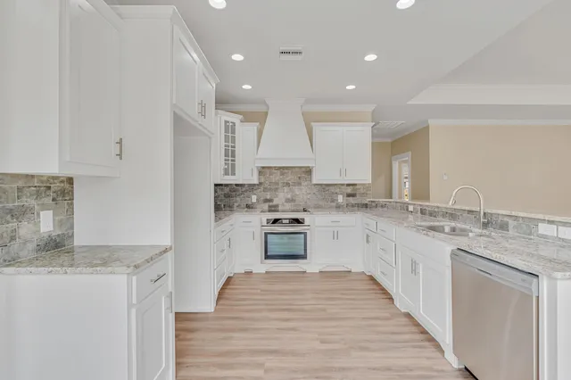 a kitchen with granite countertop white cabinets and white stainless steel appliances