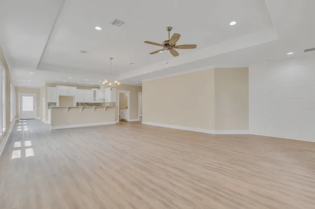an empty room with wooden floor fan and windows