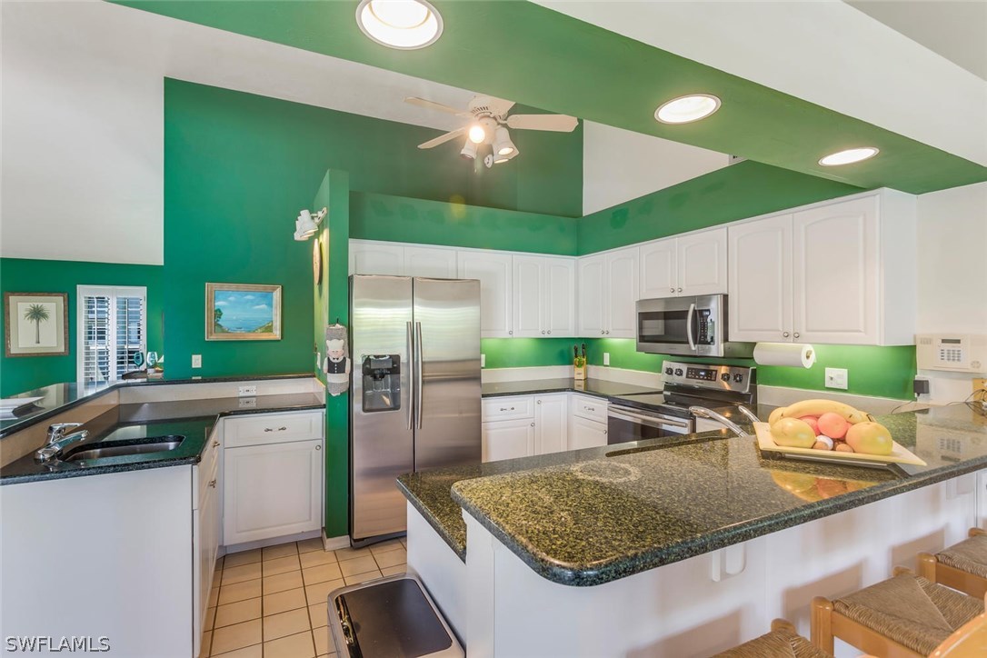 1341 Sand Castle Road Sanibel, FL 33957 - Photo 8 of 18 a kitchen with stainless steel appliances granite countertop a sink refrigerator and cabinets