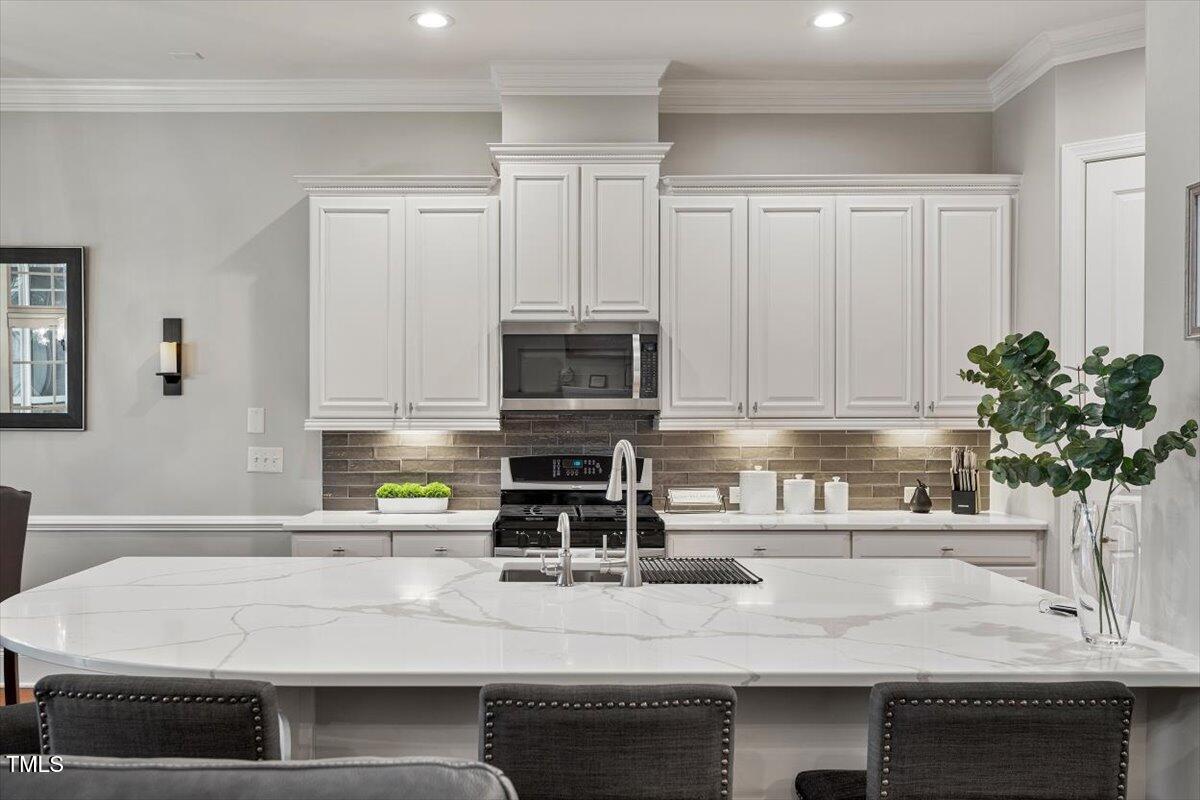 105 Sunstone Drive Cary, NC 27519 - Photo 3 of 25 a kitchen with stainless steel appliances granite countertop a sink a stove and a microwave