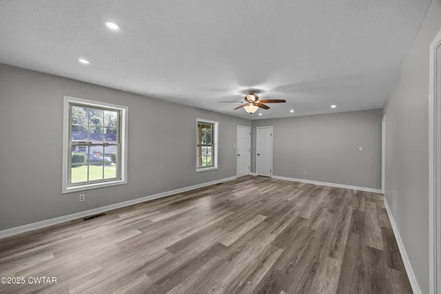 a view of an empty room with a window and wooden floor
