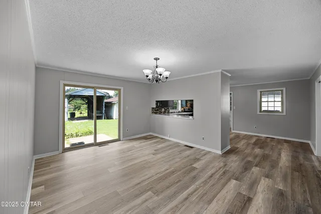 a view of an empty room with window and wooden floor