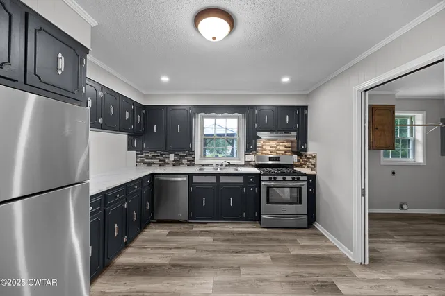 a kitchen with stainless steel appliances granite countertop a refrigerator a stove a sink and a microwave