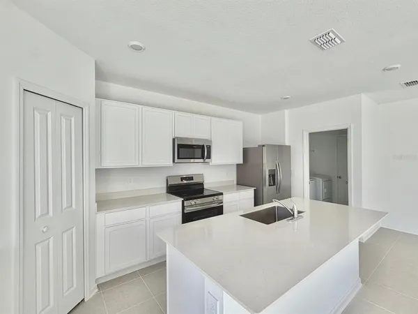 a kitchen with kitchen island white cabinets and refrigerator