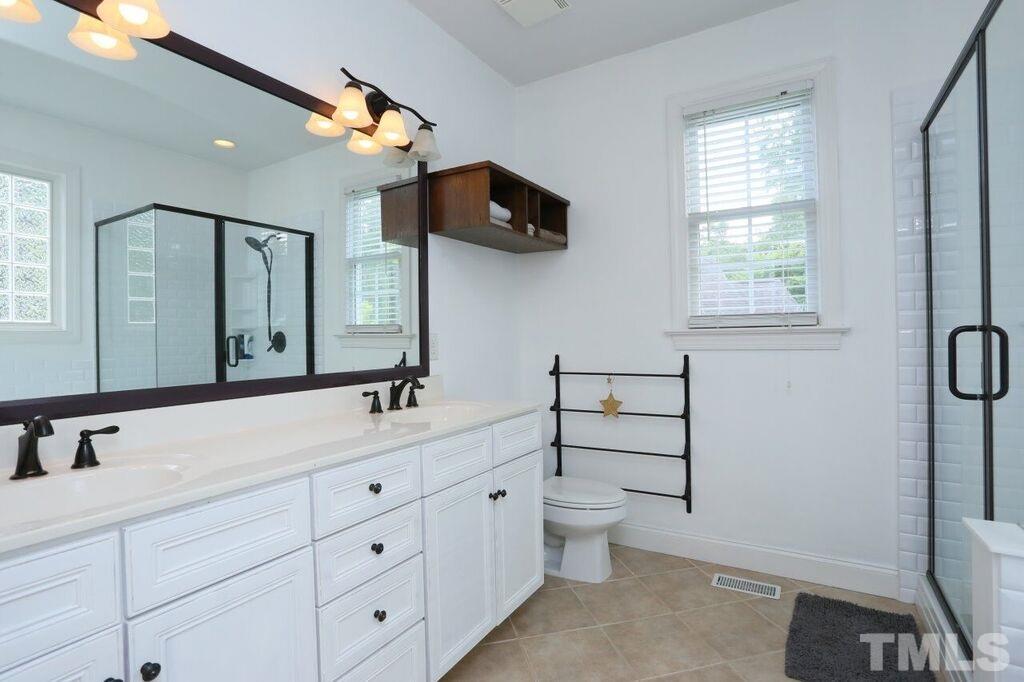 6301 Pleasant Creek Court Raleigh, NC 27613 - Photo 8 of 21 a bathroom with a double vanity sink a toilet and mirror