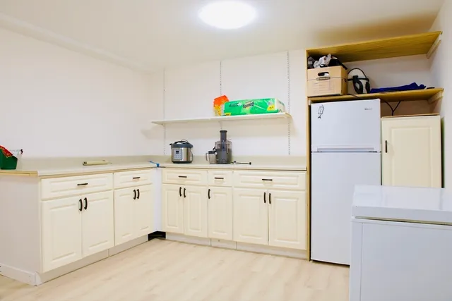 a kitchen with white cabinets and refrigerator