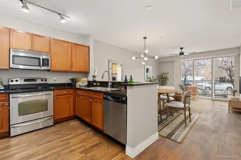 a kitchen with stainless steel appliances kitchen island granite countertop a stove top oven a sink with dining table and chairs