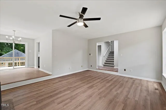 a view of a room with wooden floor large windows and a ceiling fan