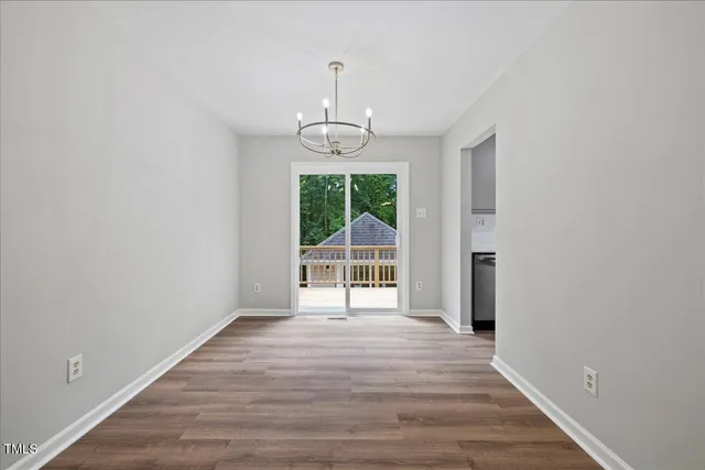 an empty room with wooden floor mirror and windows