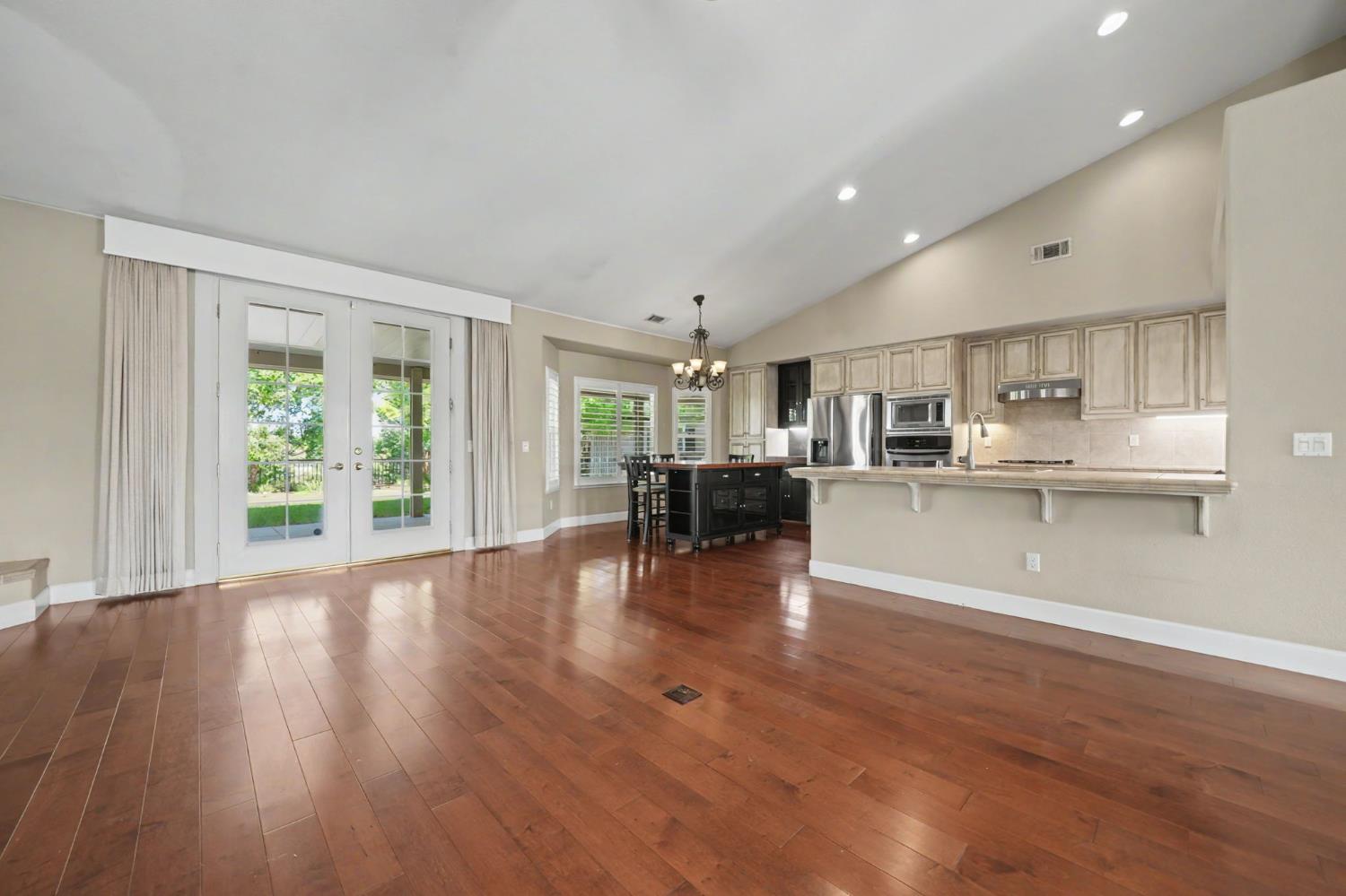532 Oakridge Road Valley Springs, CA 95252 - Photo 27 of 89 a open kitchen with kitchen island a stove a refrigerator a dining table and chairs with wooden floor