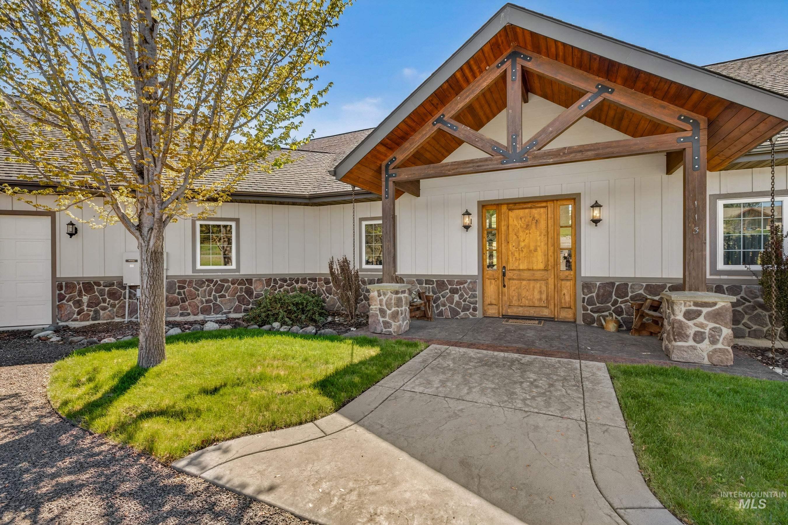 113 Deford Road White Bird, ID 83554 - Photo 7 of 49 Craftsman-style home featuring a prominent timber-framed entryway with exposed beams, a custom wood entry door, and stone accents