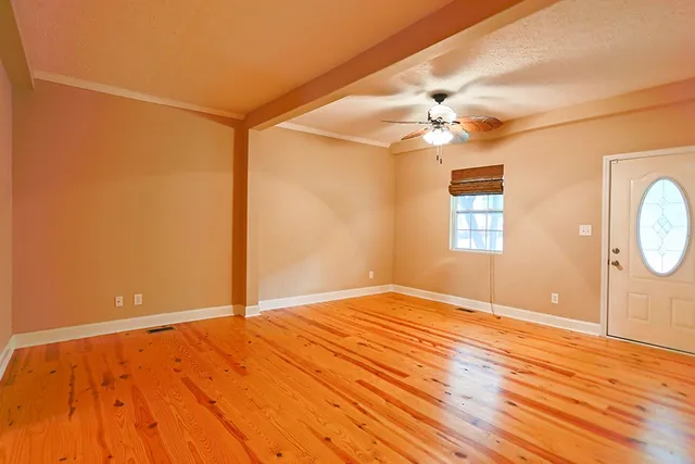 a view of an empty room with window and wooden floor
