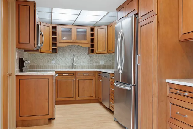 a view of a hallway with stainless steel appliances granite countertop cabinets and a refrigerator