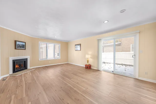 an empty room with wooden floor fireplace and windows