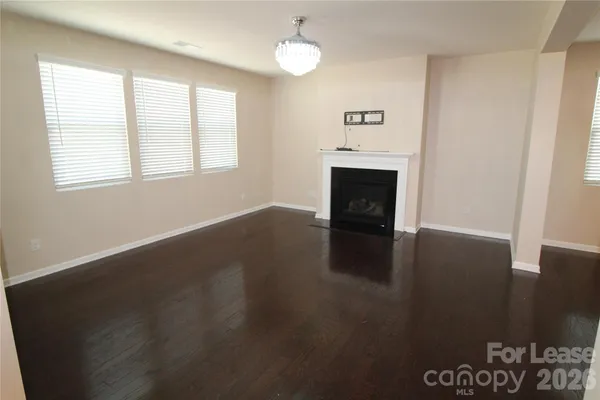 an empty room with windows fireplace and wooden floor