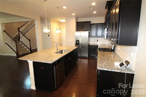 a kitchen with stainless steel appliances granite countertop a sink a stove and a wooden floors