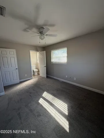 an empty room with windows and ceiling fan