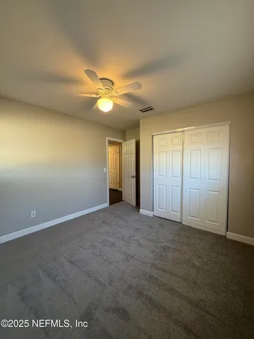 an empty room with windows and fan