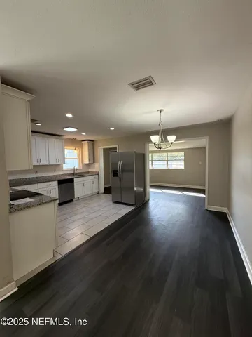 a view of a kitchen with a stove wooden cabinets and a living room