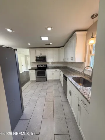 a large kitchen with stainless steel appliances granite countertop a sink and cabinets
