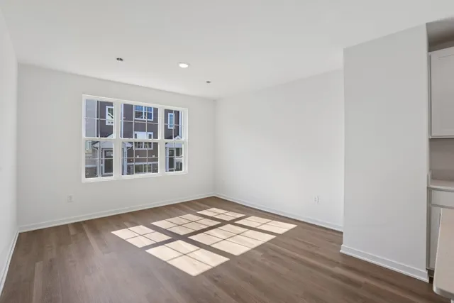an empty room with wooden floor cabinet and windows