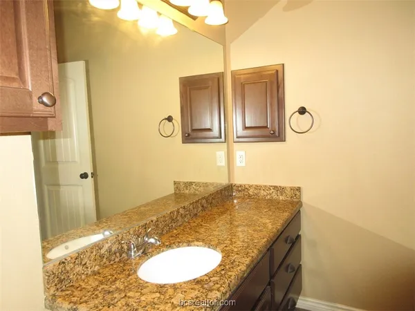 a bathroom with a granite countertop sink and a mirror