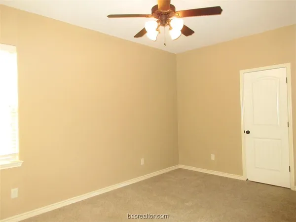 an empty room with a window and a fan