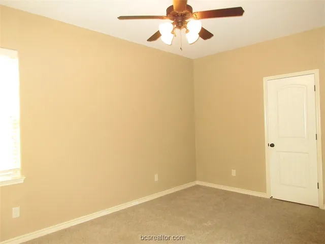 an empty room with a window and a fan