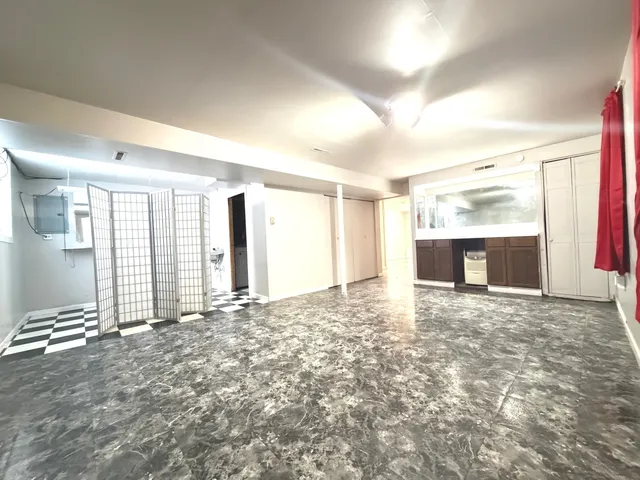a view of an empty room with window and a kitchen