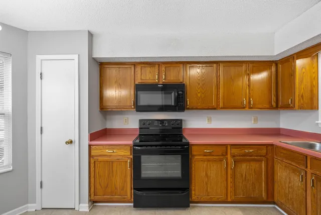 a kitchen with granite countertop wooden cabinets and a stove top oven