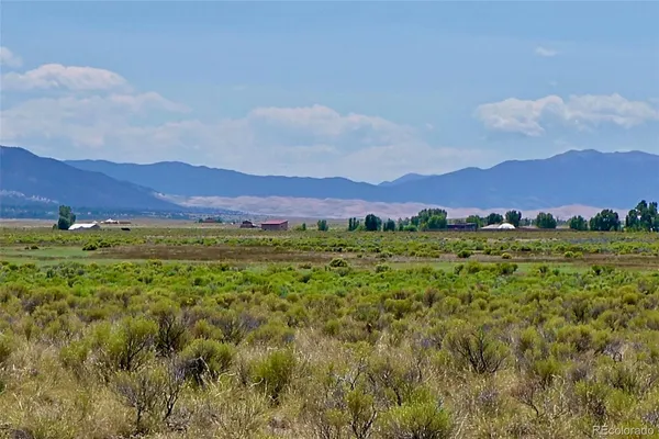 a view of a lush green field with mountains in the background